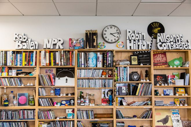 A Tiny Desk-style set: shelves of records, a band behind a desk